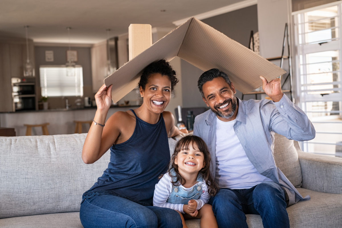 smiling family sitting under cardboard roof